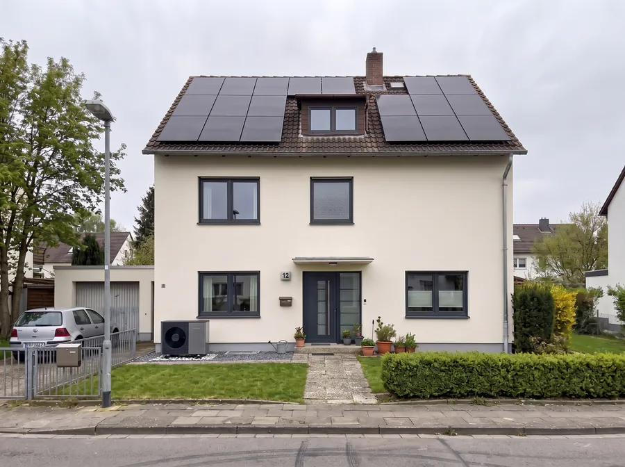 Dasselbe Haus nach der Sanierung: gedämmte Fassade, neue Fenster, Photovoltaik auf dem Dach